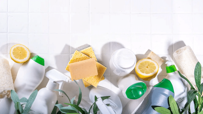 Eco friendly cleaning products - brushes, sponges, soap, bottles with green leaves on white background